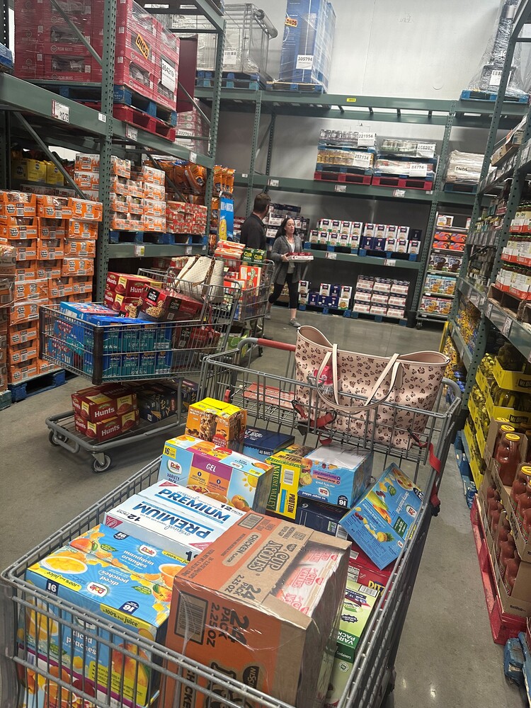 Two shopping carts full of food items in the aisle of a shopping center.