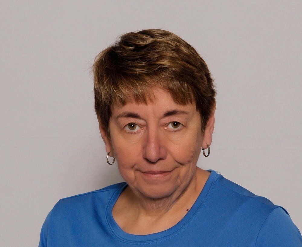 A headshot of a woman in a blue shirt smiling slightly at the camera.