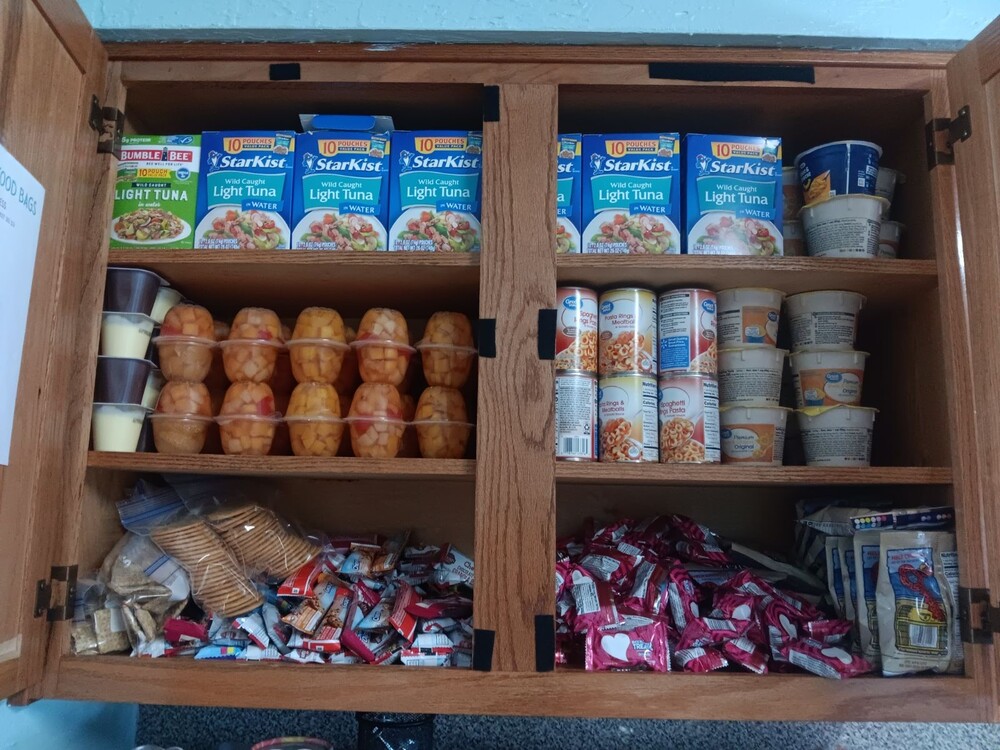 A cabinet loaded with non-perishable foods such as tuna, soup, fruit cups, etc.