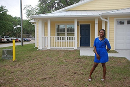 A woman standing in front of a yellow house