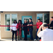 A group of men and women cutting a large ribbon. 