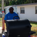 Man cooking hot dogs on a grill.