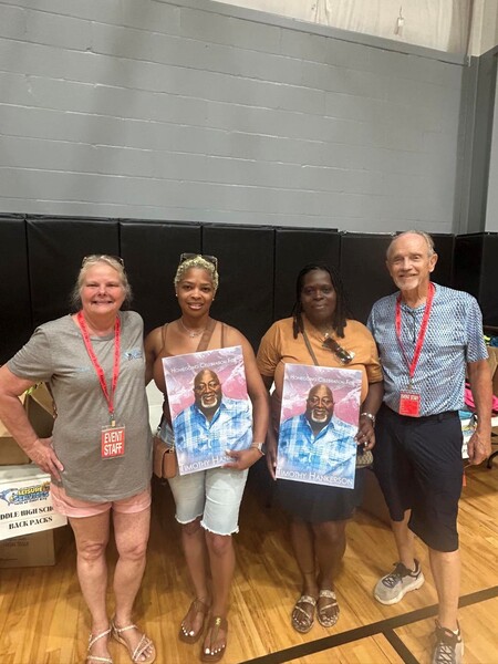 Executive Director Teresa Pope standing with three others, two of which are holding signs honoring the late Tim Hankerson